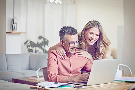 Happy middle aged couple using laptop.